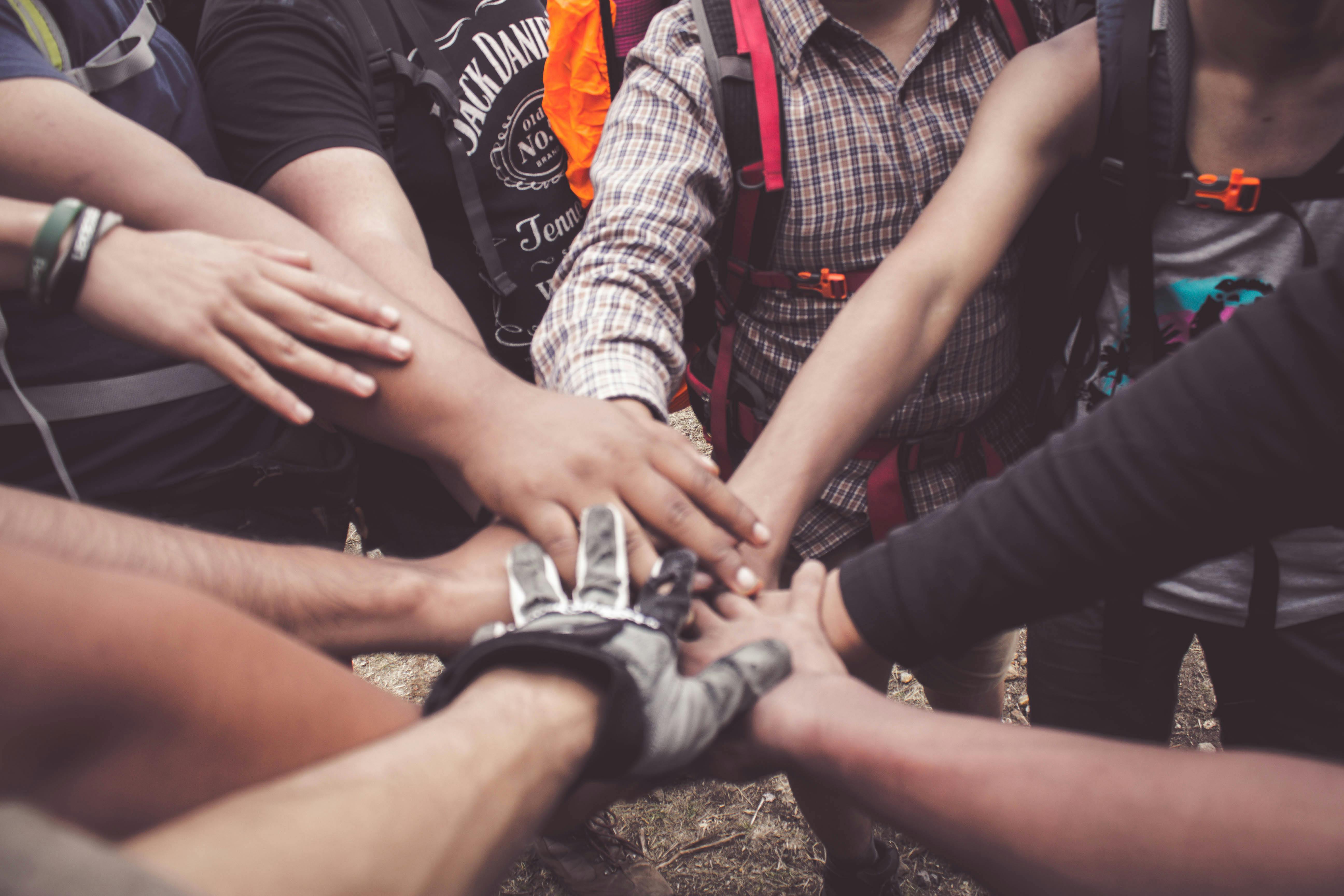 A picture of a group of people in a circle, with their hands stacked in the center